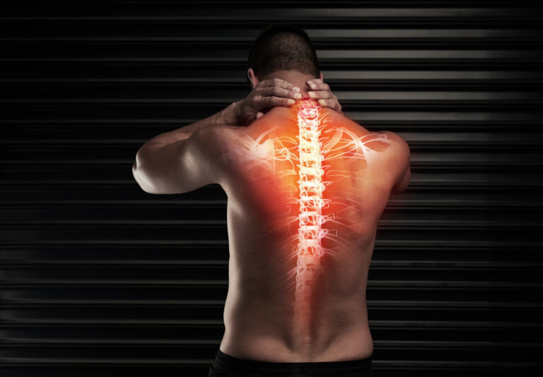 Rearview shot of an athletic young man suffering with a back injury in the studio